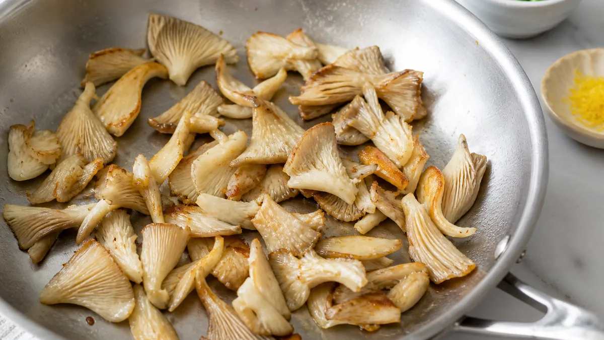 Torn oyster mushrooms seared before adding to mushroom risotto - best mushrooms for risotto