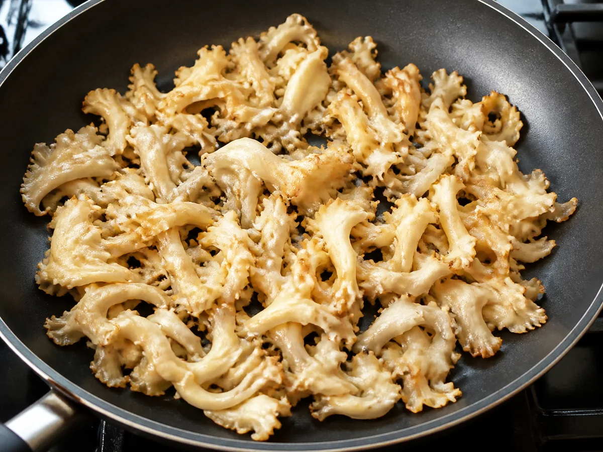 Clean cauliflower mushroom curls in one loose skillet layer with pale golden edges and visible separation