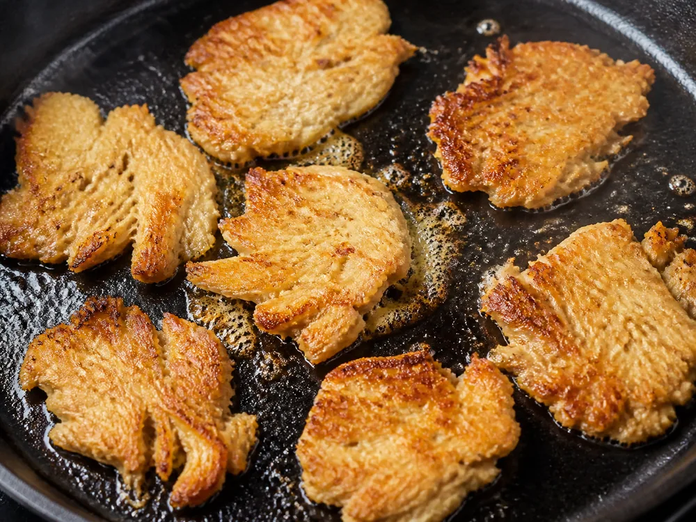 Golden lion's mane pieces with broad browned faces in a skillet