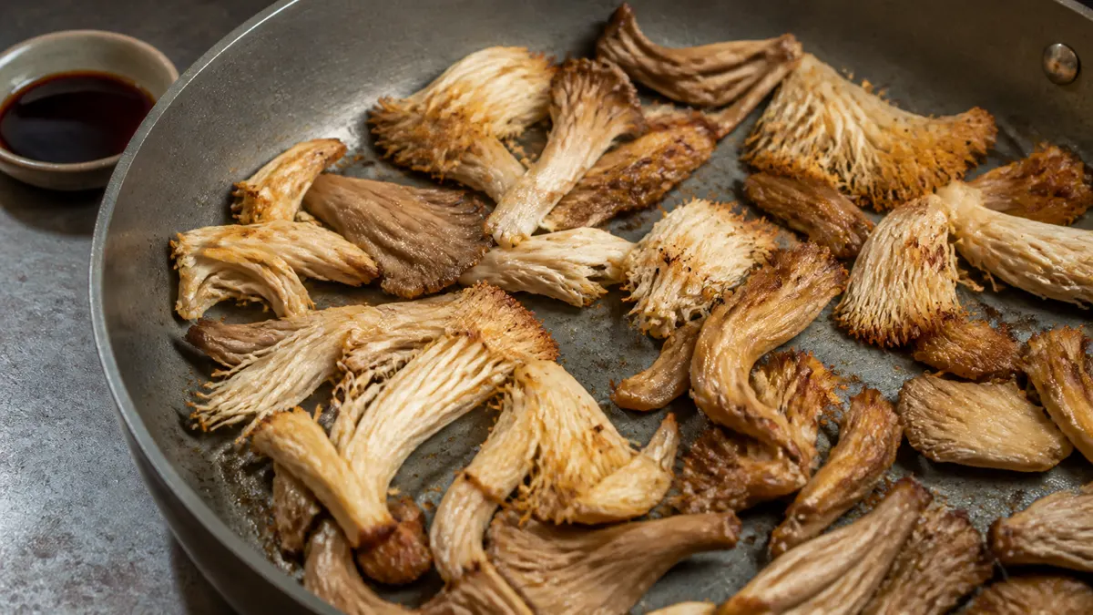 Browned mushroom shreds in a wide pan with open metal and no pooled water