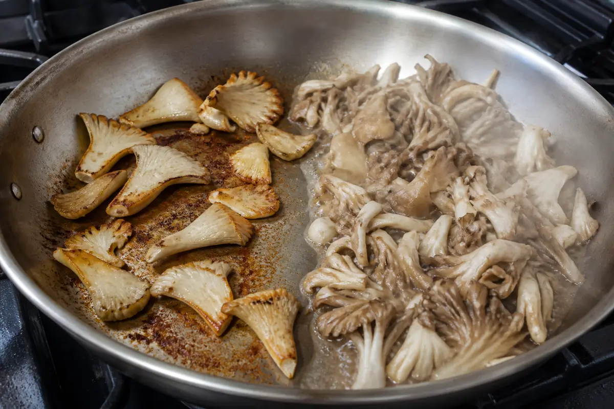 Browned oyster and maitake mushrooms beside a crowded wet area in a wide skillet