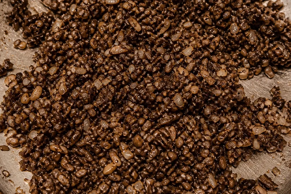 Finely chopped mature wine cap mushrooms cooking down with shallot in a pan into a dark concentrated duxelles