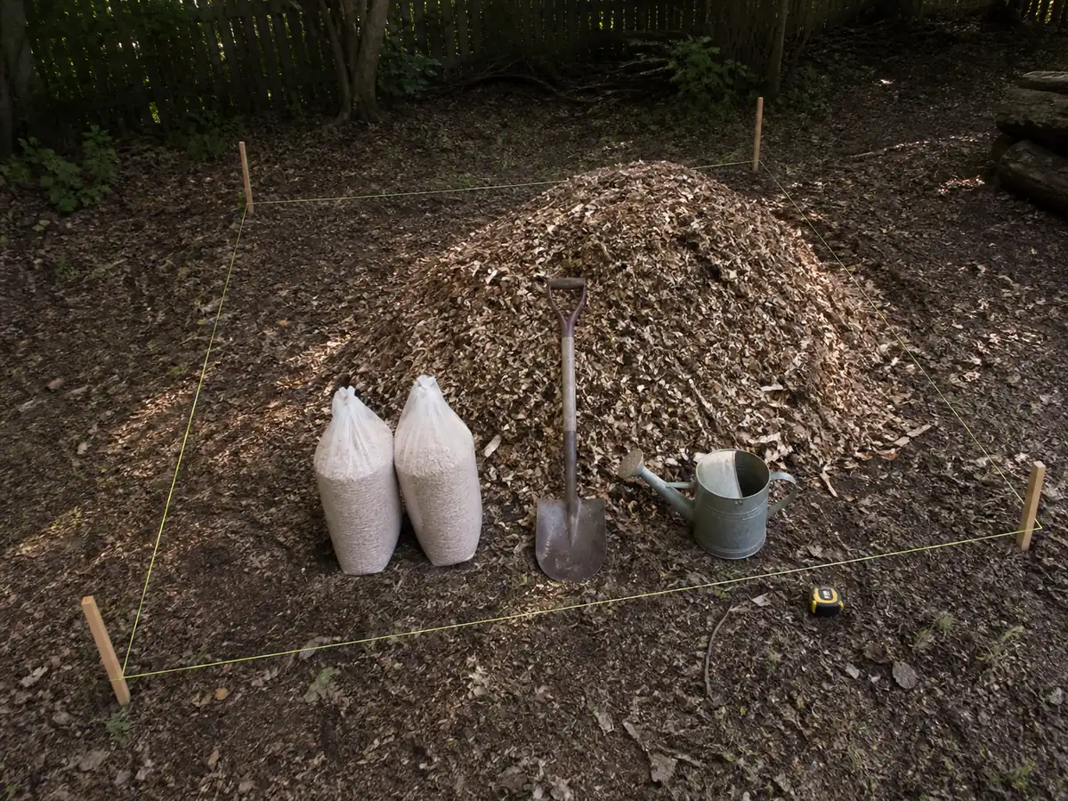 Measured hardwood chips and mushroom spawn beside a marked four-by-eight-foot garden bed