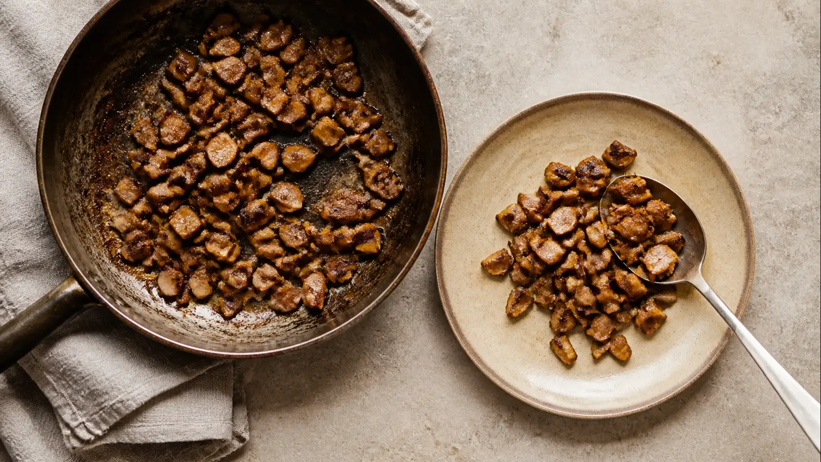 Browned morel pieces being served from a wide skillet