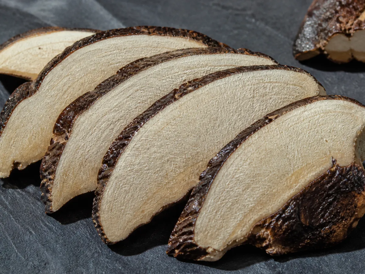 Thin slices of a woody bracket fungus fanned out showing pale cut faces and dark crust edges