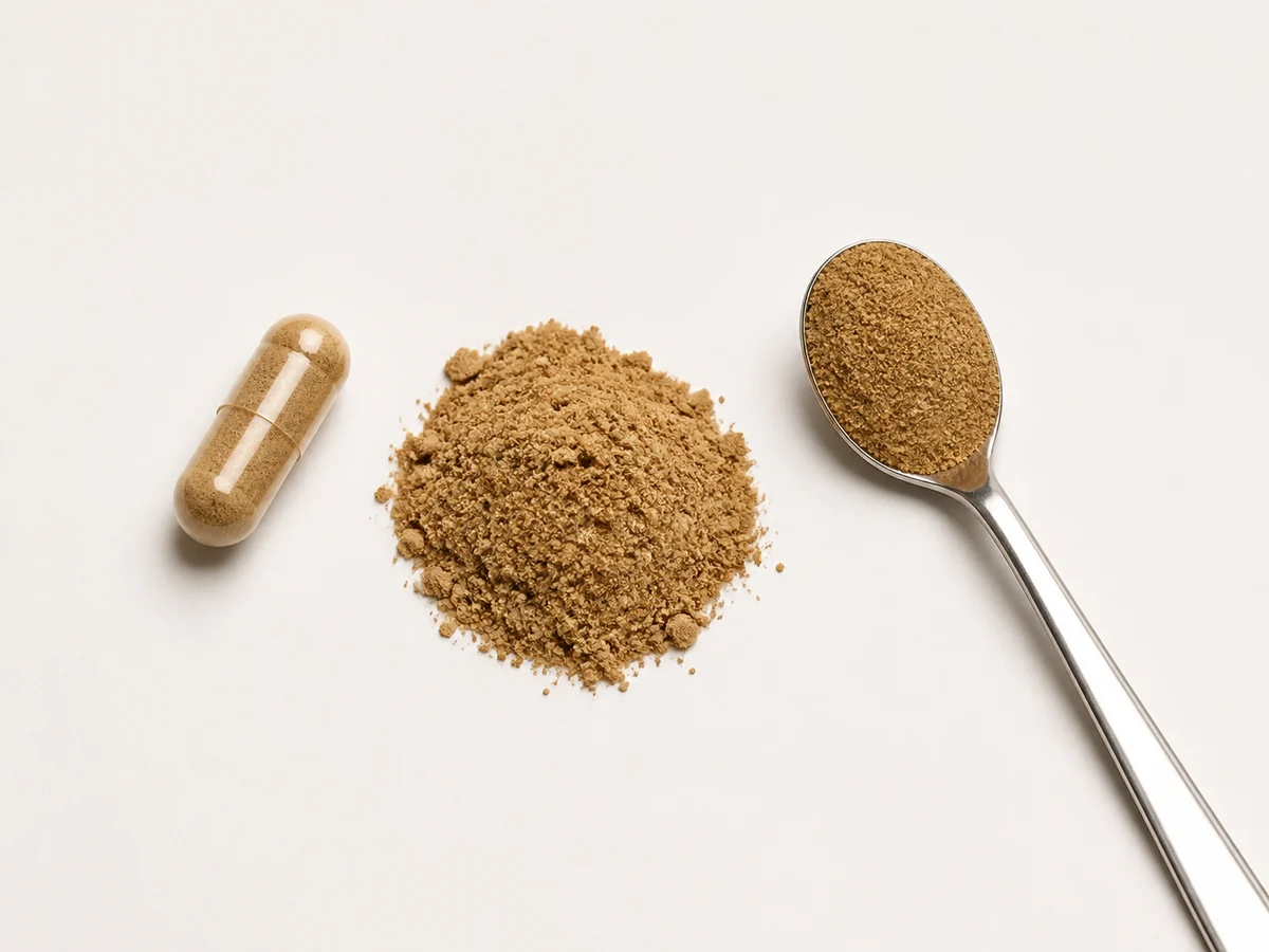 Single supplement capsule beside a small mound of dried mushroom powder and a level teaspoon