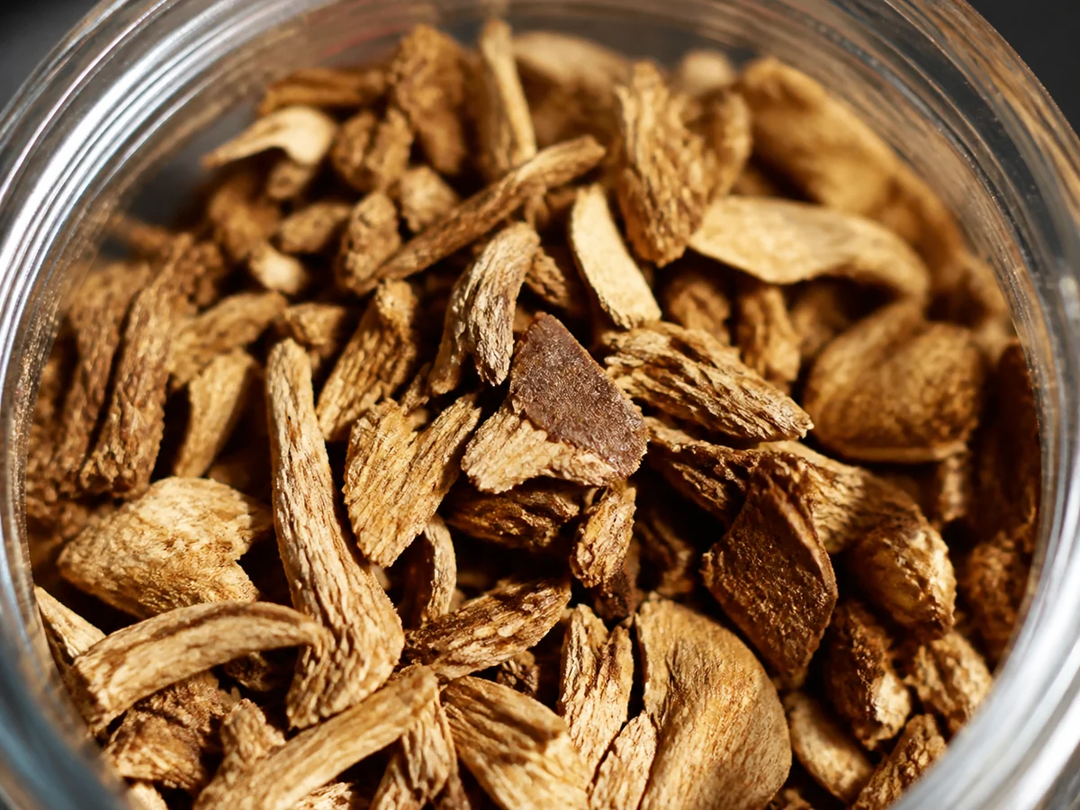 Extreme close-up of coarse dried mushroom flakes and fragments in an open glass jar