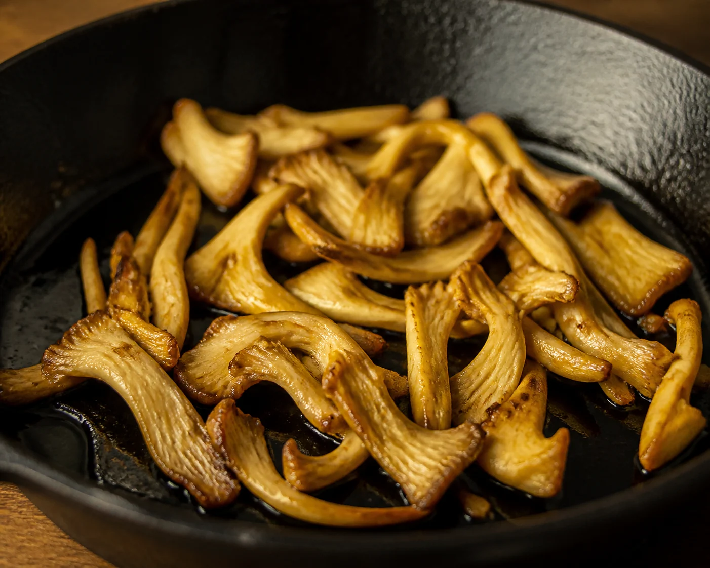 Strips of golden oyster mushroom browned in a cast iron pan, the bright yellow faded to pale tan and gold