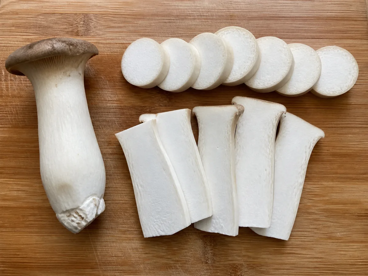 King oyster rounds and lengthwise steaks cooking beside a dinner fork for scale - king oyster cut thickness